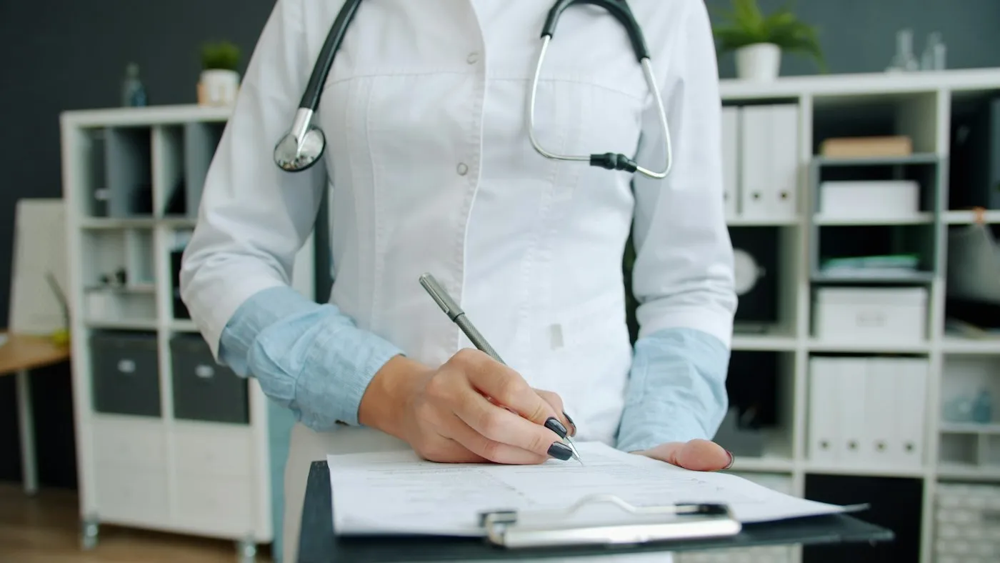 A clinician filling in a form on a clipboard