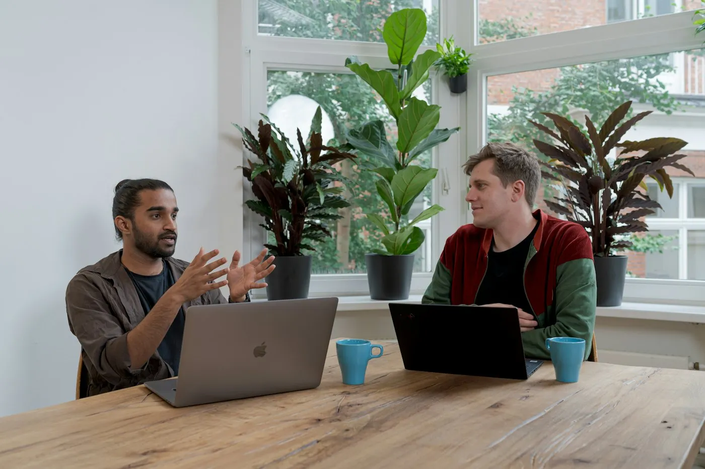 Two people in a calm one-on-one conversation at a table by a window