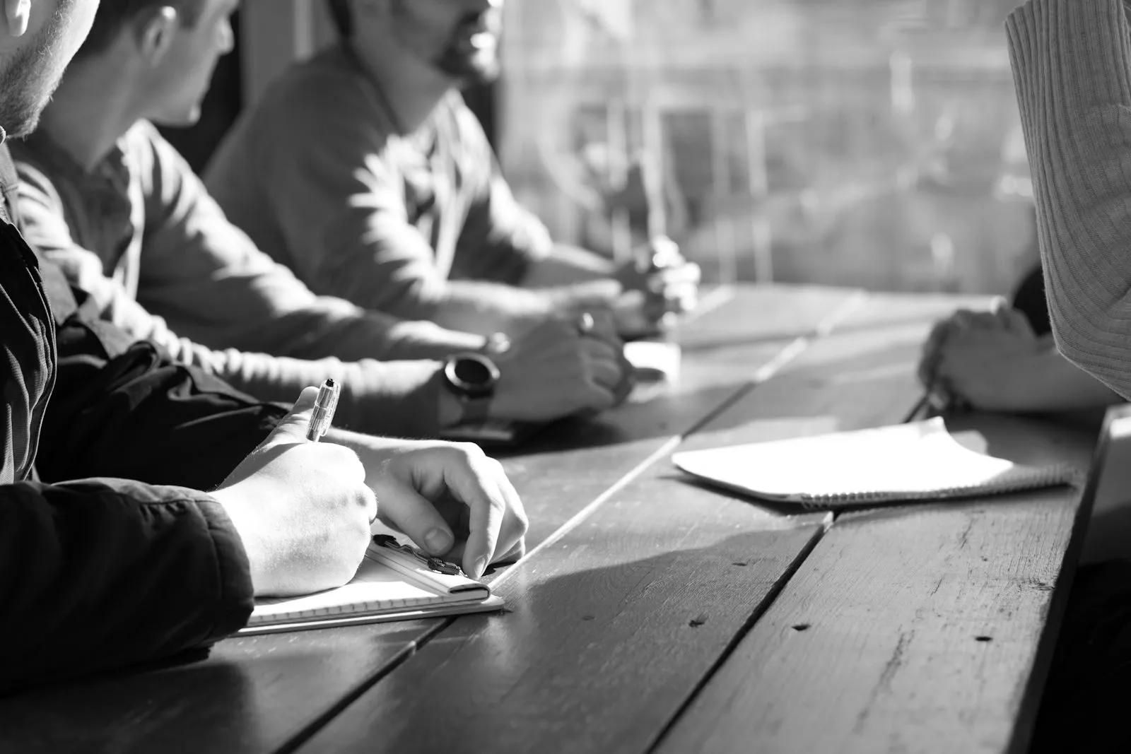 A team taking notes around a wooden meeting table