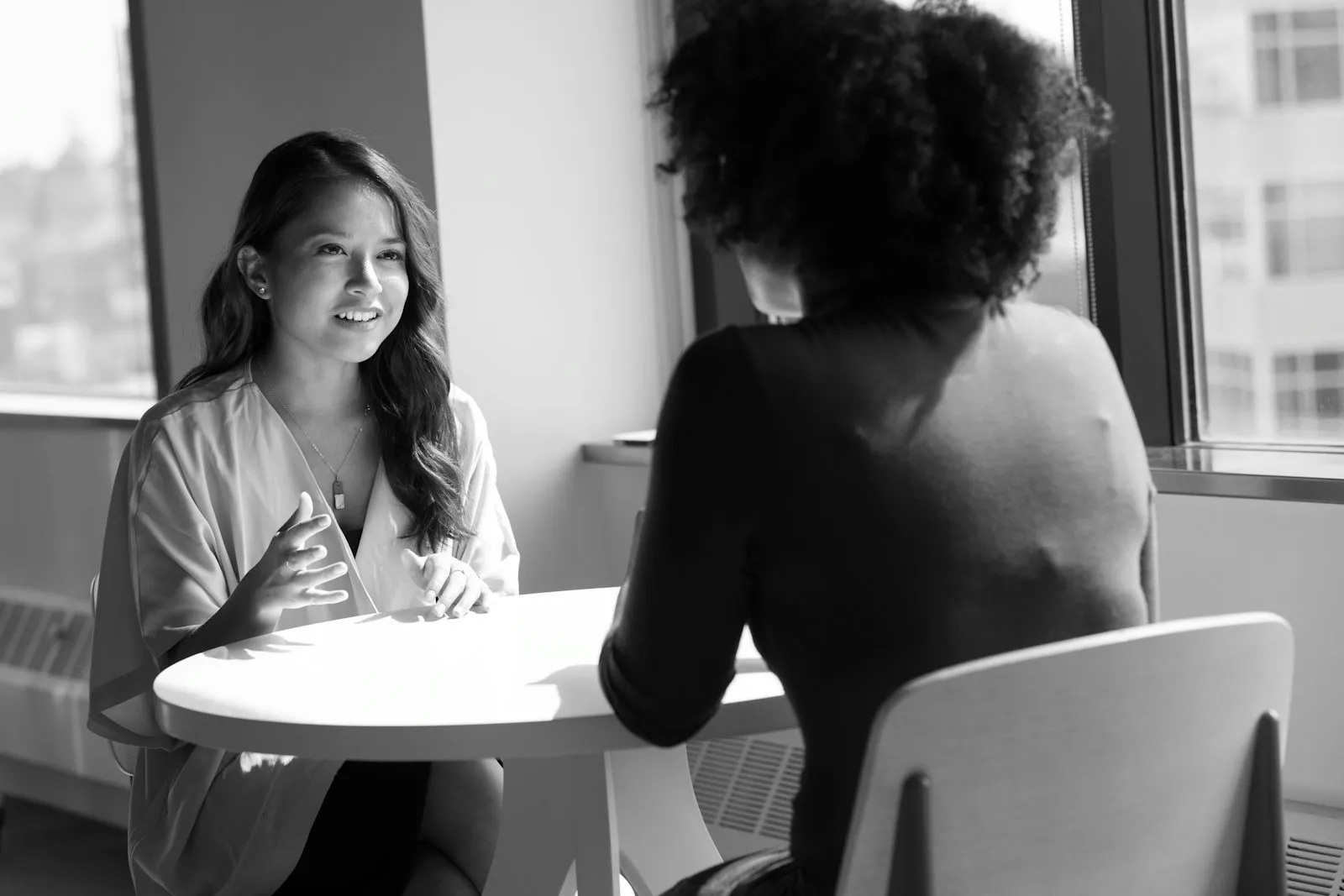 Two colleagues in a private conversation at a small table by a window