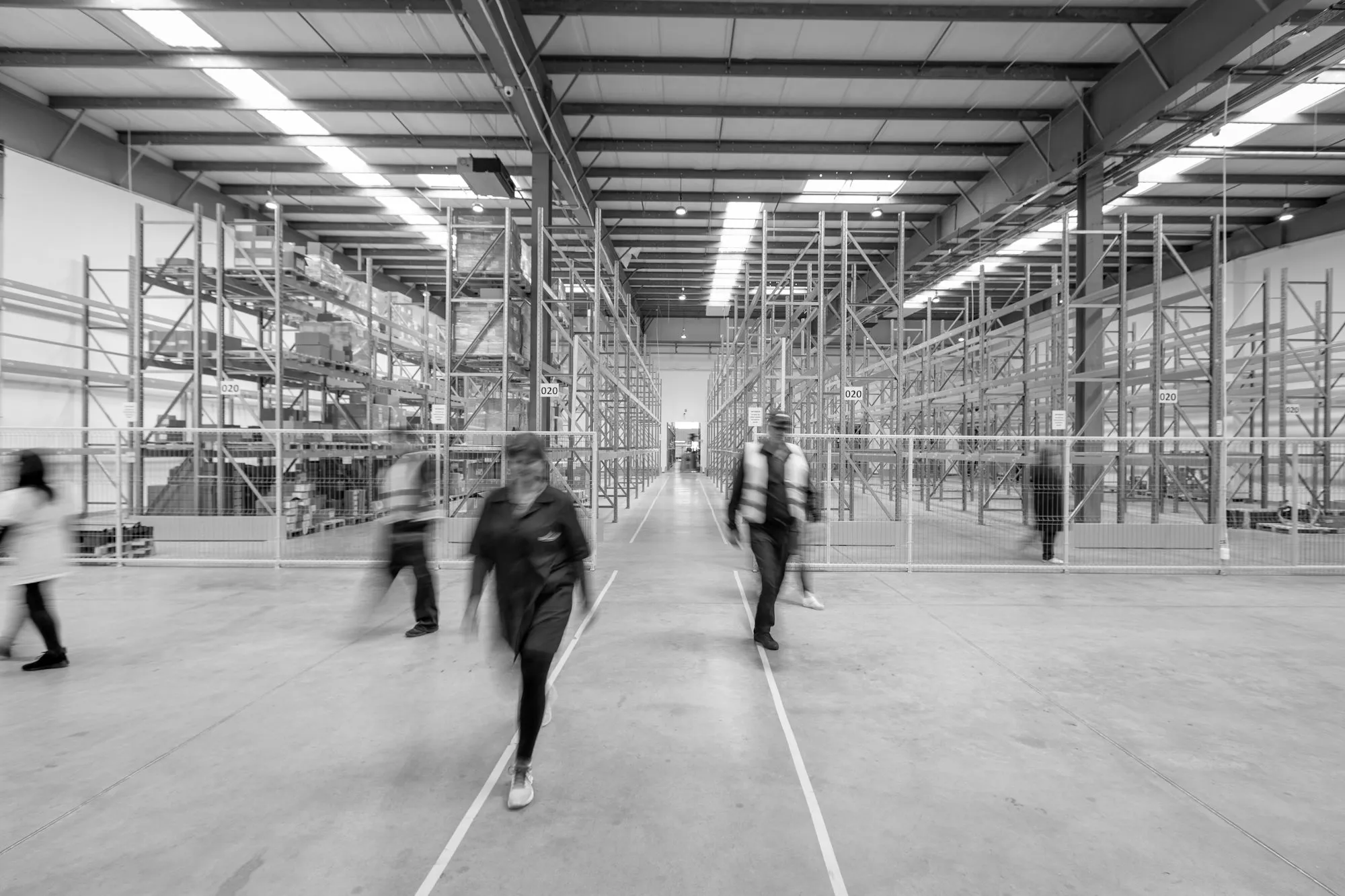 Staff walking along a wide warehouse aisle between storage racks