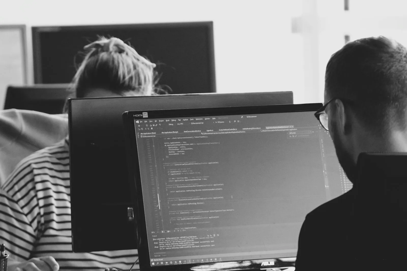 An engineer reading code on a monitor in a shared office