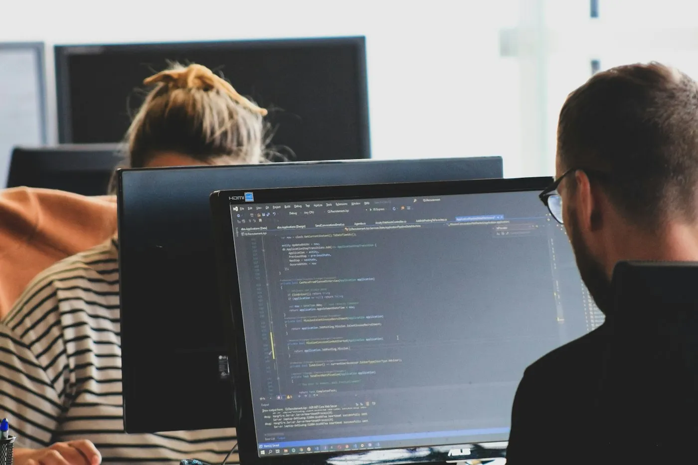 Two engineers working at monitors showing code